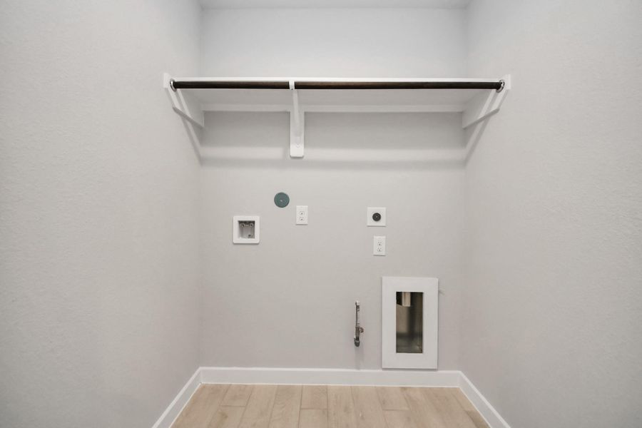 A perfect blend of functionality and comfort. Capture the essence of easy living with a first-floor laundry room, thoughtfully equipped with shelving for effortless organization. Both electric and gas connections available. Sample photo of completed home with similar floor plan. Actual colors and selections may vary.