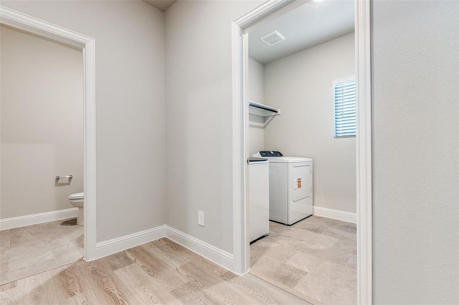Laundry room with light wood finished floors and washing machine and clothes dryer Laundry room with light wood finished floors and washing machine and clothes dryer