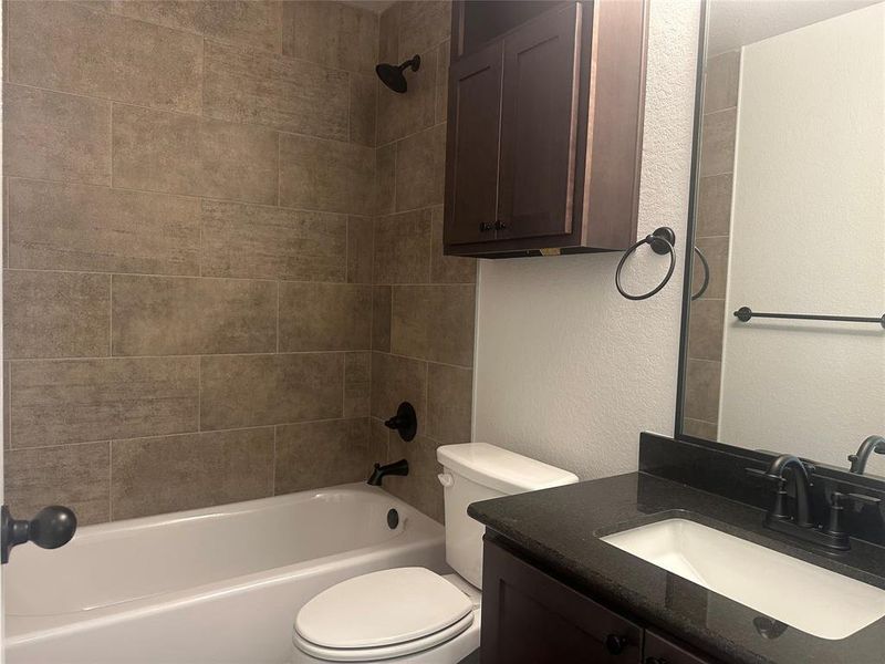 Bathroom featuring vanity, shower / bath combination, and a textured wall