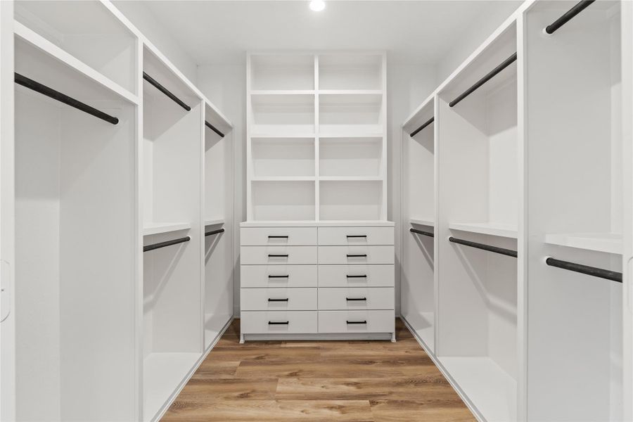 Custom walk-in closet with built-in shelving, double hanging space, and extra storage drawers.