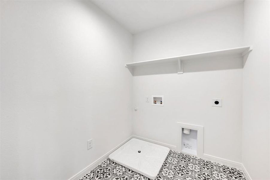 Utility space featuring patterned black and white floor tiles, a built-in white shelf, and all-white walls