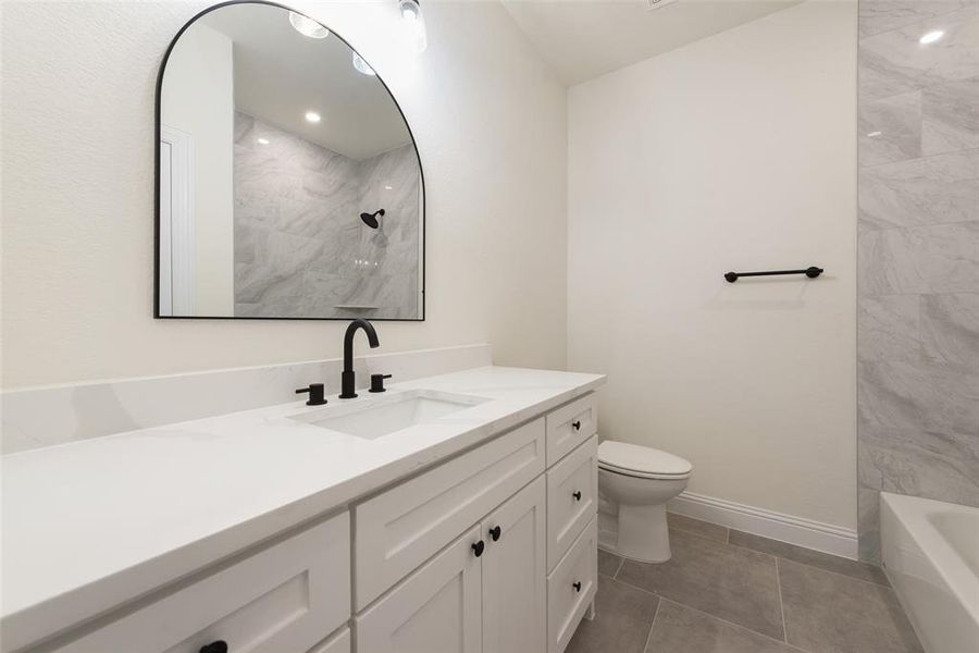 Full bathroom featuring tiled shower / bath, vanity, toilet, and tile patterned floors