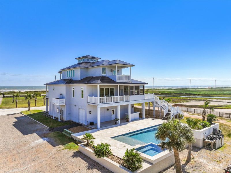 This striking side view invites you to imagine life on your private slice of paradise. The sparkling saltwater pool stretches toward the horizon, while unobstructed Gulf vistas promise endless sunrises. Picture lounging poolside with a cocktail, morning swims under golden light, and every day feeling like a vacation. Notice the Golf Cart/ATV garage door on the side of the house.