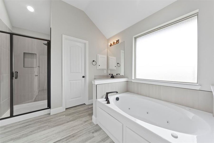 Bathroom featuring vanity, wood-type flooring, lofted ceiling, and shower with separate bathtub