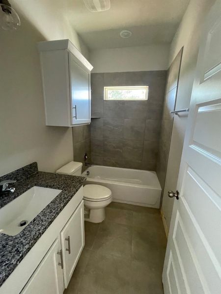 Full bathroom with toilet, tiled shower / bath combo, and vanity