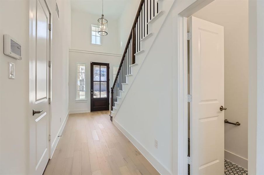 Entryway featuring light wood-type flooring and a towering ceiling