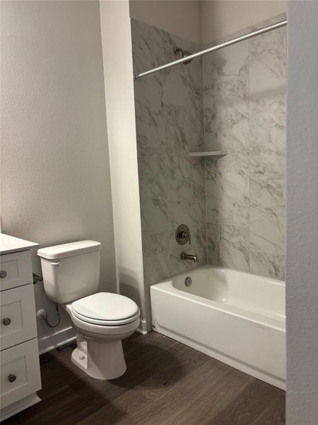Full bath with shower / tub combination, vanity, a textured wall, and dark wood-style floors