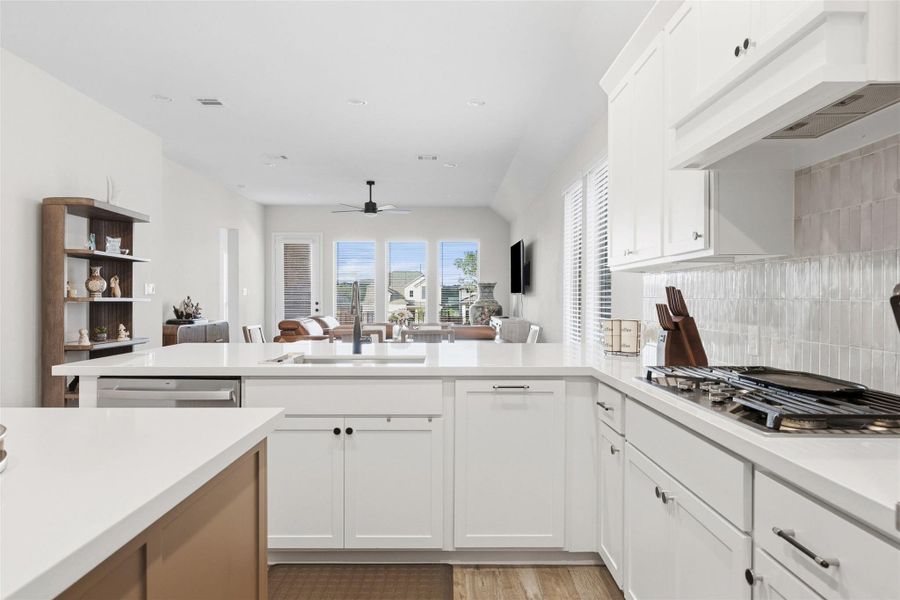 Contemporary kitchen featuring white cabinetry, light-toned countertops, a built-in dishwasher, and a gas cooktop