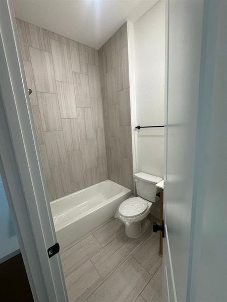 Bathroom featuring a white bathtub, light-toned tile flooring, and matching tile shower surround