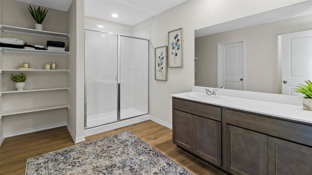 Full bath featuring dark wood-type flooring, a stall shower, vanity, and a closet