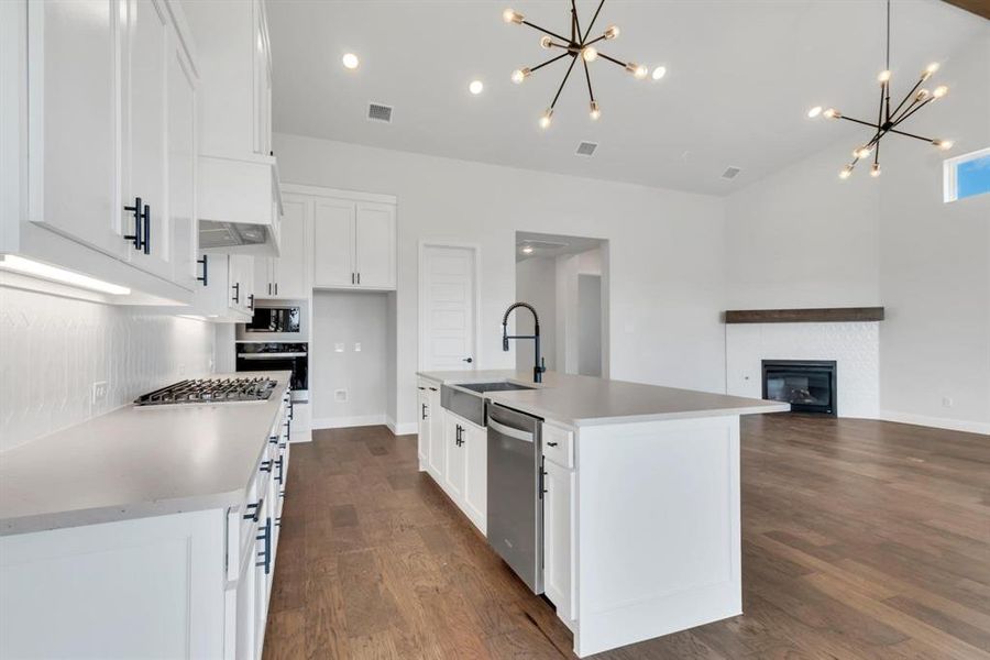 Kitchen featuring black appliances, a fireplace, dark hardwood / wood-style flooring, sink, and a kitchen island with sink