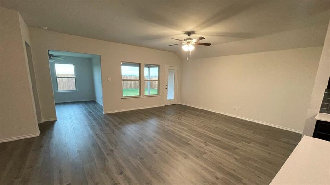 Spacious interior featuring wood-finish flooring, recessed ceiling with a ceiling fan, three pane windows, and a glass-paneled exterior door