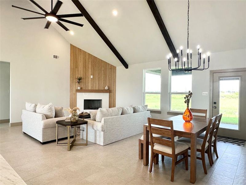 Dining space with high vaulted ceiling, beamed ceiling, a fireplace, a chandelier, and ceiling fan