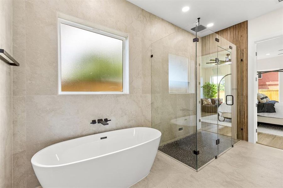 Contemporary bathroom featuring a freestanding soaking tub with wall-mounted matte black fixtures, a spacious glass-enclosed shower with a rainfall showerhead and dark pebble flooring, and a decorative vertical wood slat accent wall