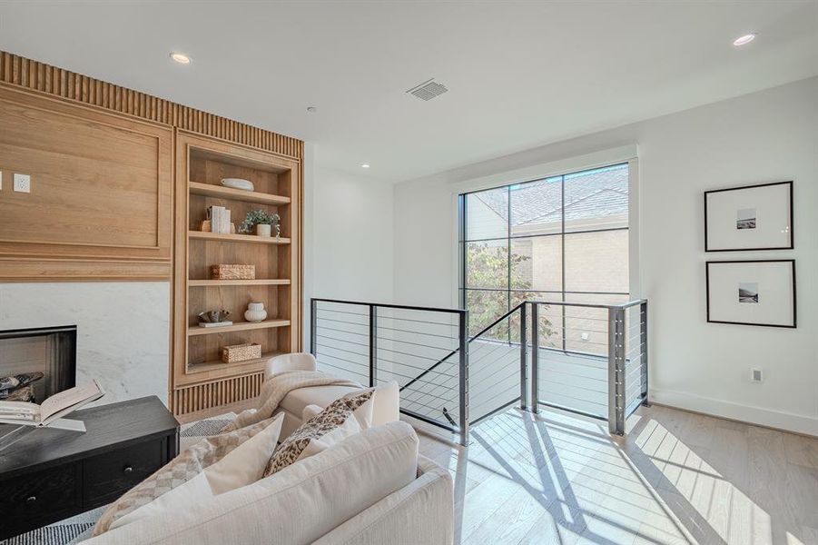 Living area with built in shelves, an upstairs landing, recessed lighting, light wood finished floors, and a fireplace Living area with built in shelves, an upstairs landing, recessed lighting, light wood finished floors, and a fireplace