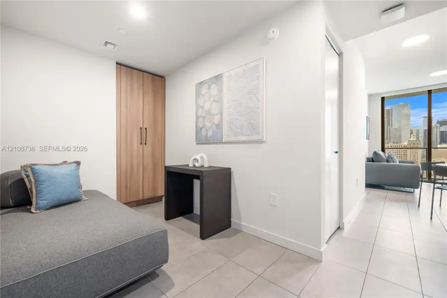 Floor-to-ceiling windows with urban skyline exposure, tile flooring, and a floor-to-ceiling wooden cabinetry unit Floor-to-ceiling windows with urban skyline exposure, tile flooring, and a floor-to-ceiling wooden cabinetry unit