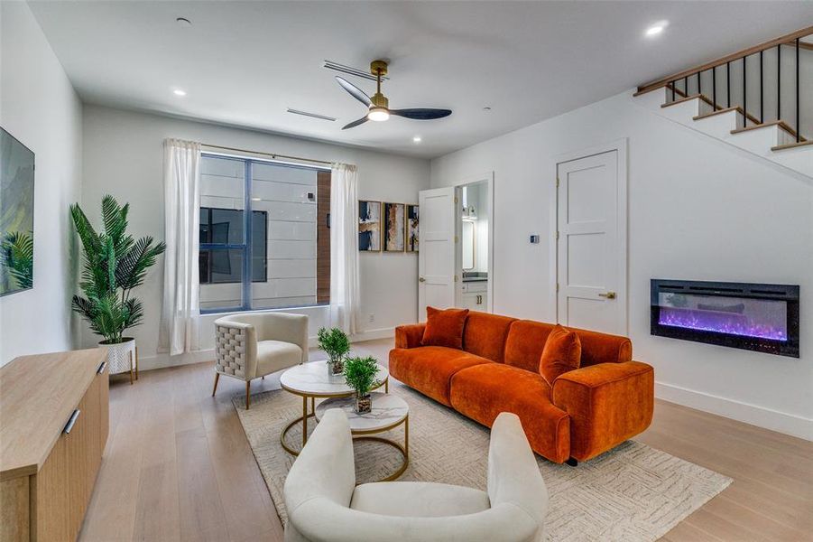 Model Home Living area featuring light wood-style floors, a glass covered fireplace, ceiling fan, and recessed lighting