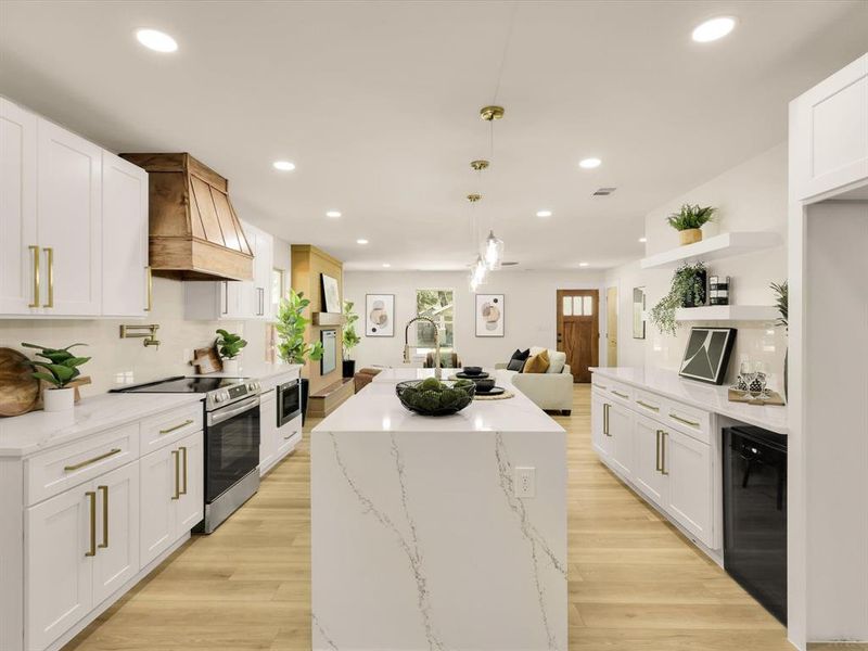 Kitchen with stainless steel appliances, custom range hood, and white cabinetry