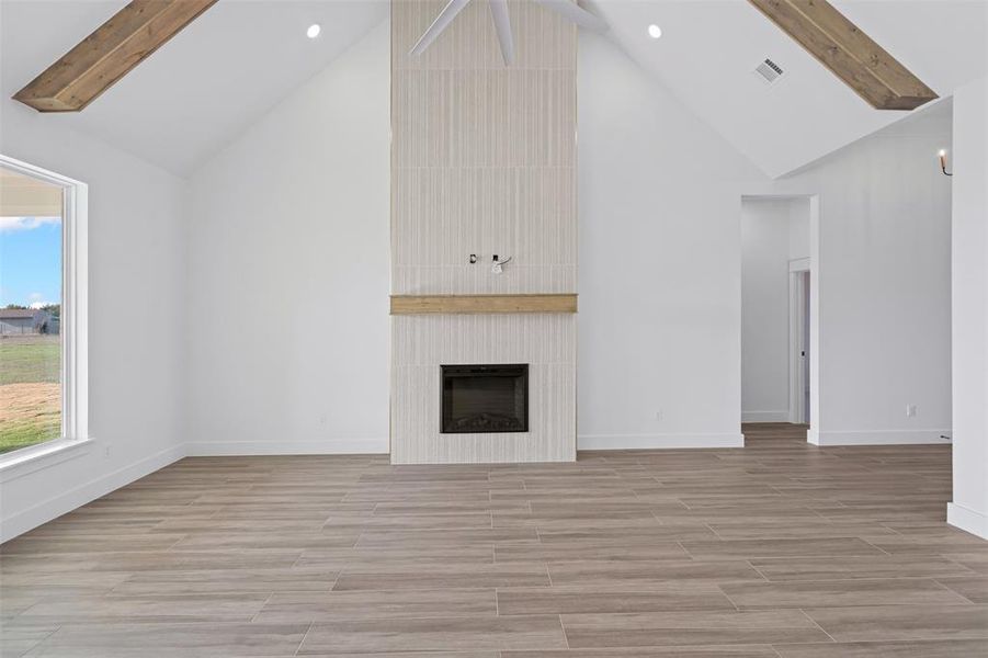 Unfurnished living room with a large fireplace, a healthy amount of sunlight, and high vaulted ceiling