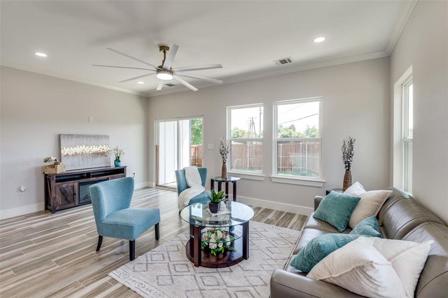 Living room with ceiling fan, light wood-type flooring, and ornamental molding