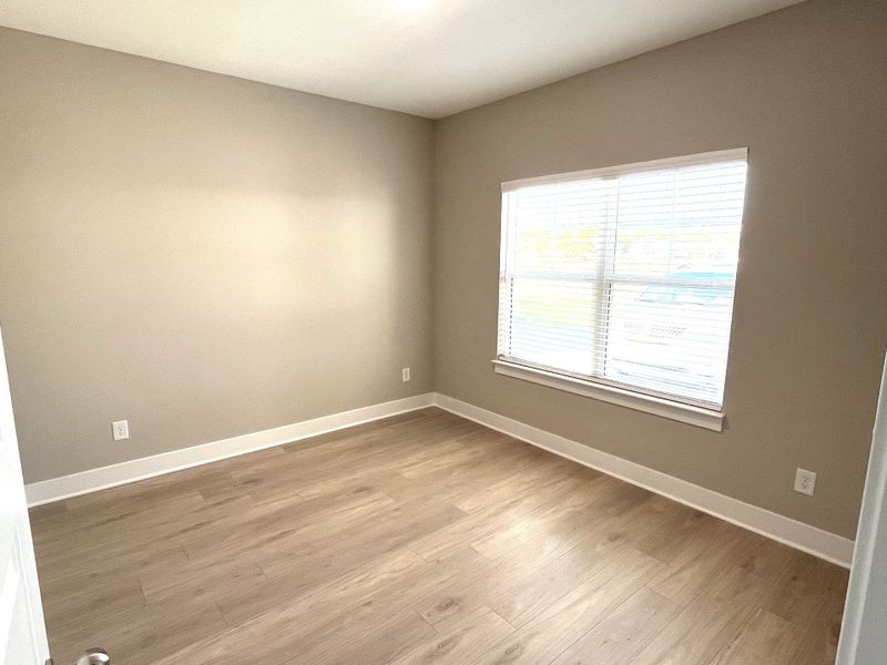 Home office up front with large window and laminate flooring