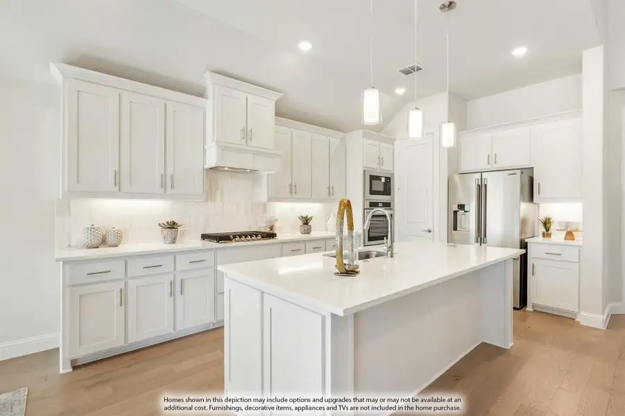 White kitchen with large center island, pendant lights, stainless steel appliances, and light wood floors