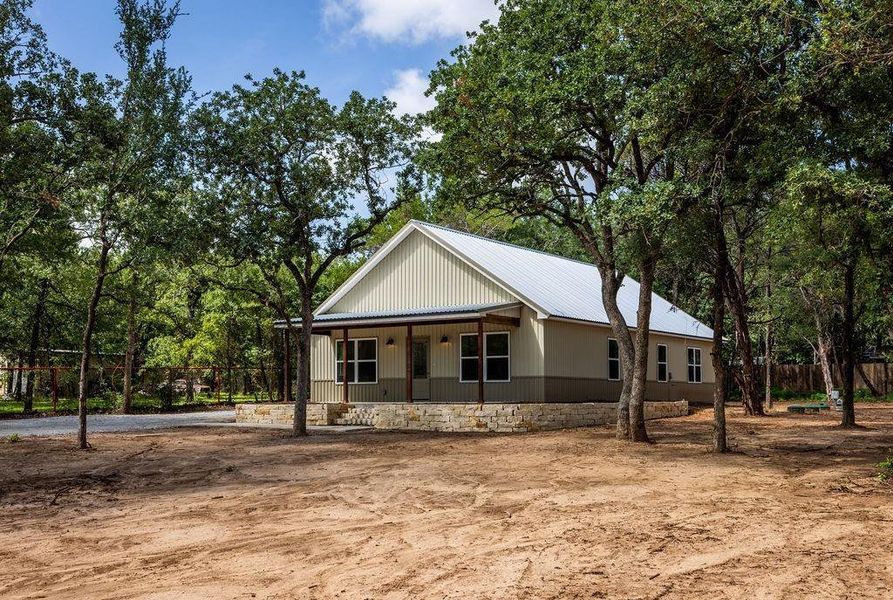 View of front of property with a porch, a metal roof, and view of wooded area