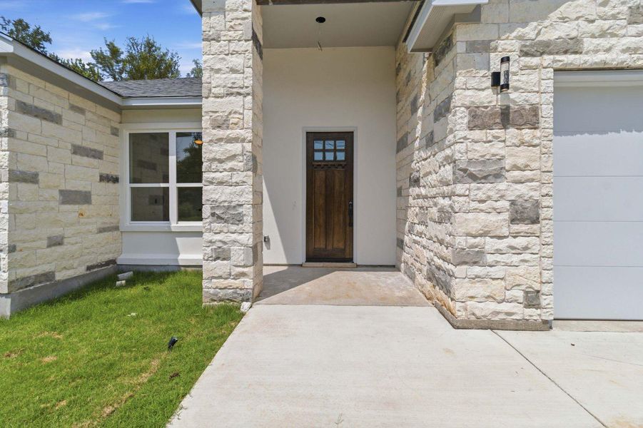 A welcoming entry framed by textured stone siding, offering a blend of modern and classic architectural elements. A welcoming entry framed by textured stone siding, offering a blend of modern and classic architectural elements.