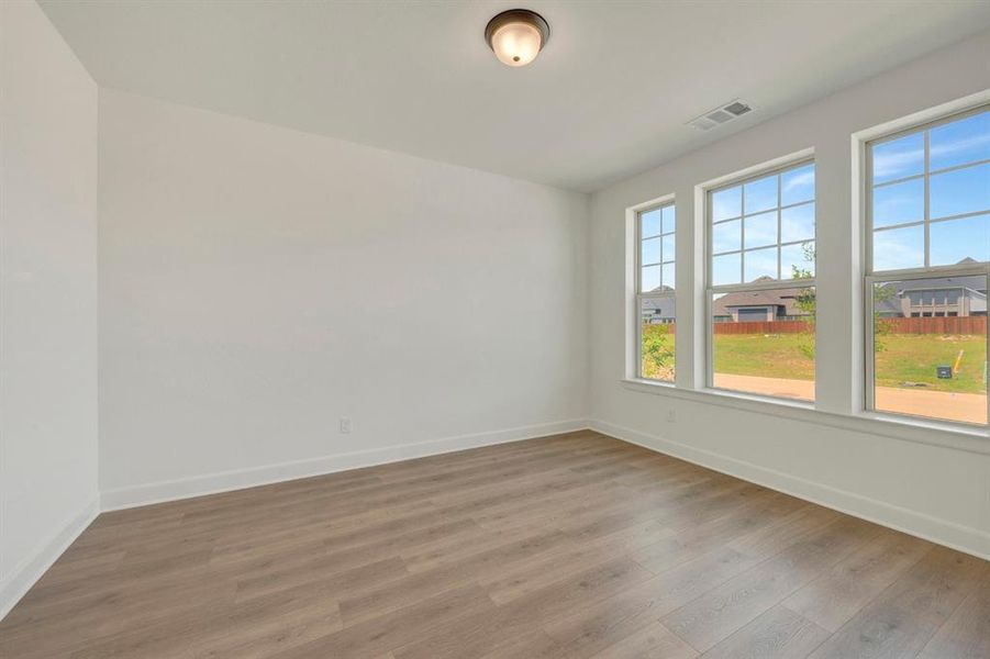 Spacious room featuring wood-finish flooring and white baseboards