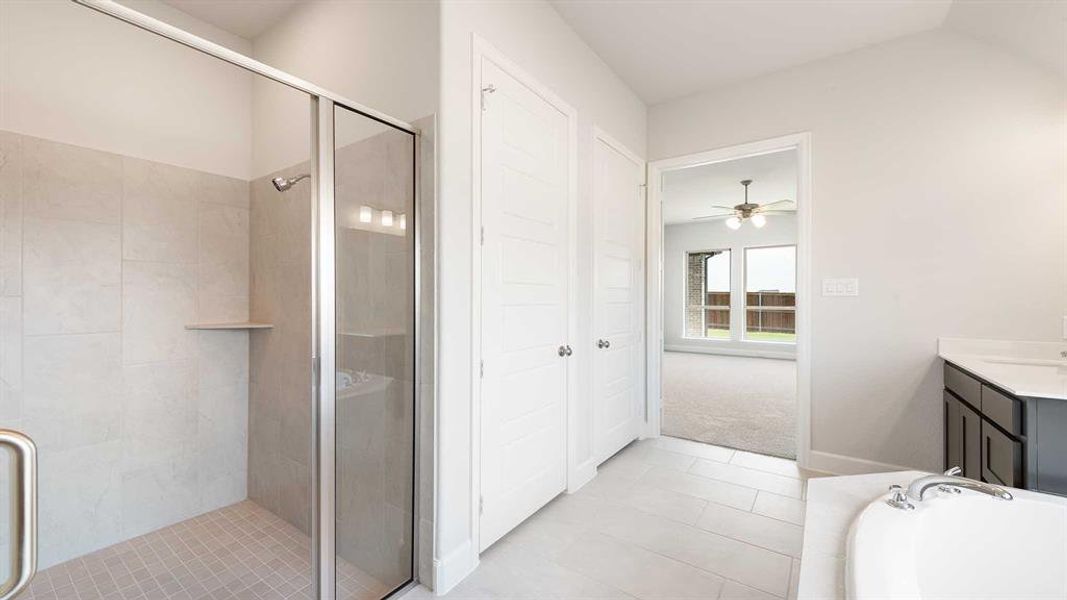 Bathroom with vanity, ceiling fan, vaulted ceiling, and plus walk in shower