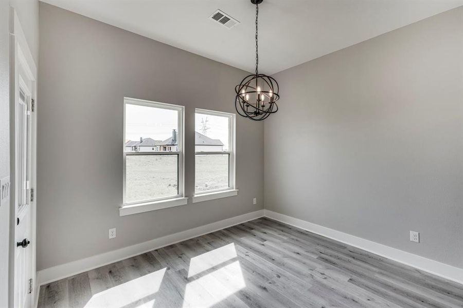 Empty room with an inviting chandelier and light hardwood / wood-style floors