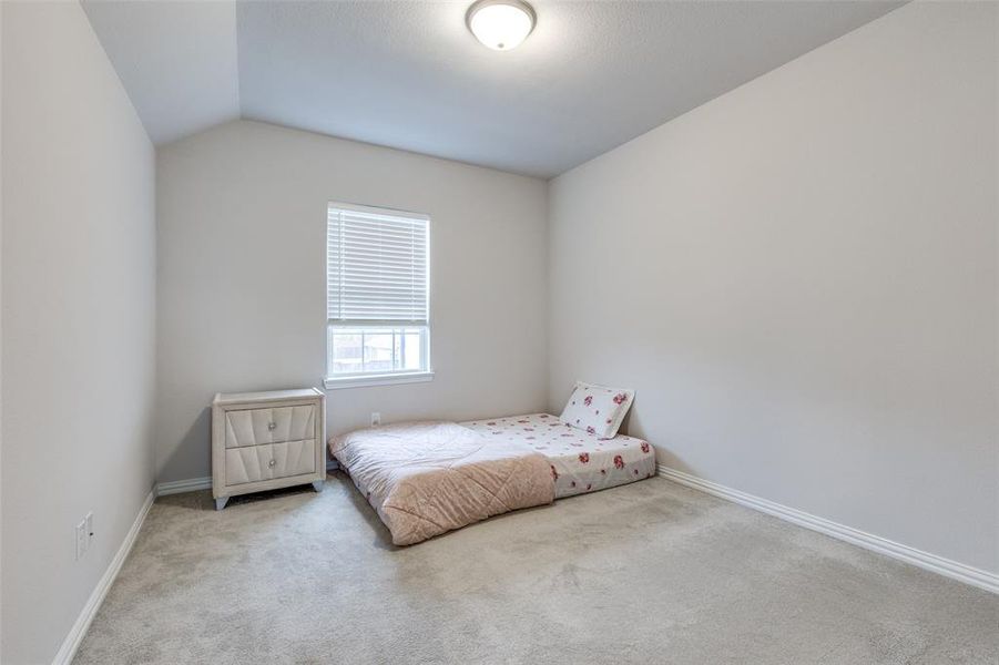 Bedroom featuring light carpet and lofted ceiling