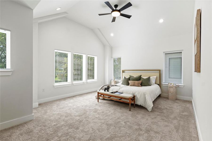 Bedroom with light carpet, high vaulted ceiling, multiple windows, a ceiling fan, and recessed lighting Bedroom with light carpet, high vaulted ceiling, multiple windows, a ceiling fan, and recessed lighting