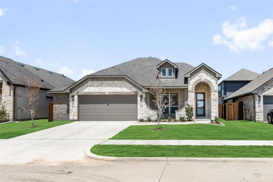 Single-story home with stone and brick exterior, two-car garage, arched entry, and green front lawn Single-story home with stone and brick exterior, two-car garage, arched entry, and green front lawn