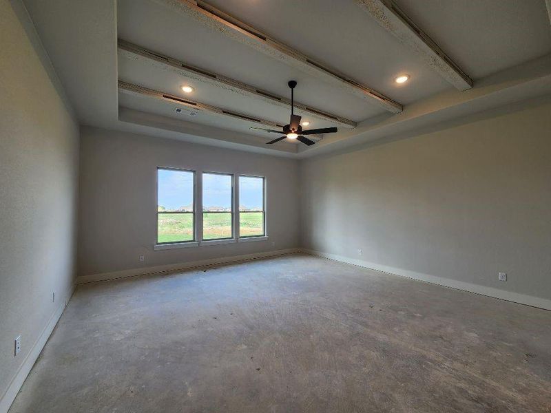 Expansive room featuring a tray ceiling with wood-finish beams and recessed lighting