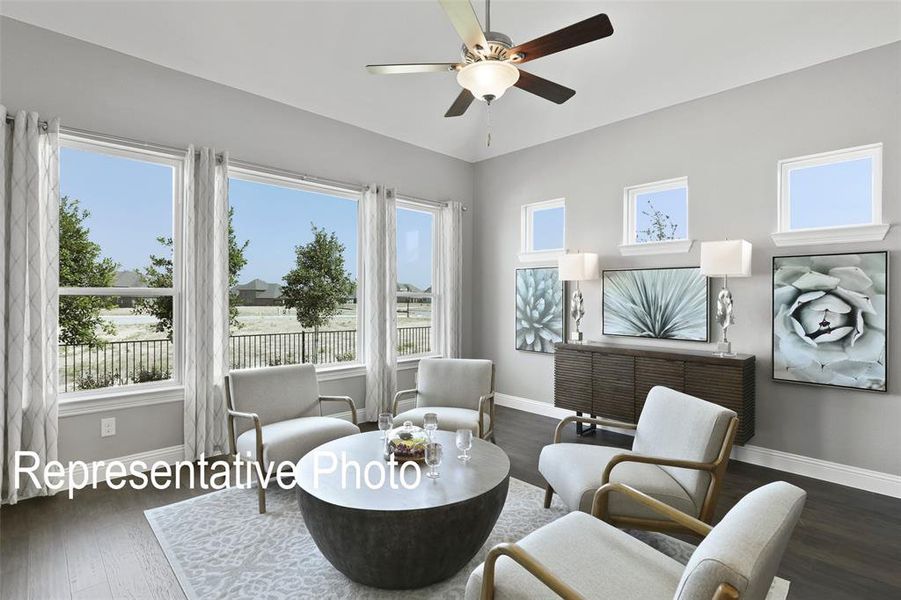 Living area featuring multiple large windows, wood-finish flooring, and a ceiling fan Living area featuring multiple large windows, wood-finish flooring, and a ceiling fan