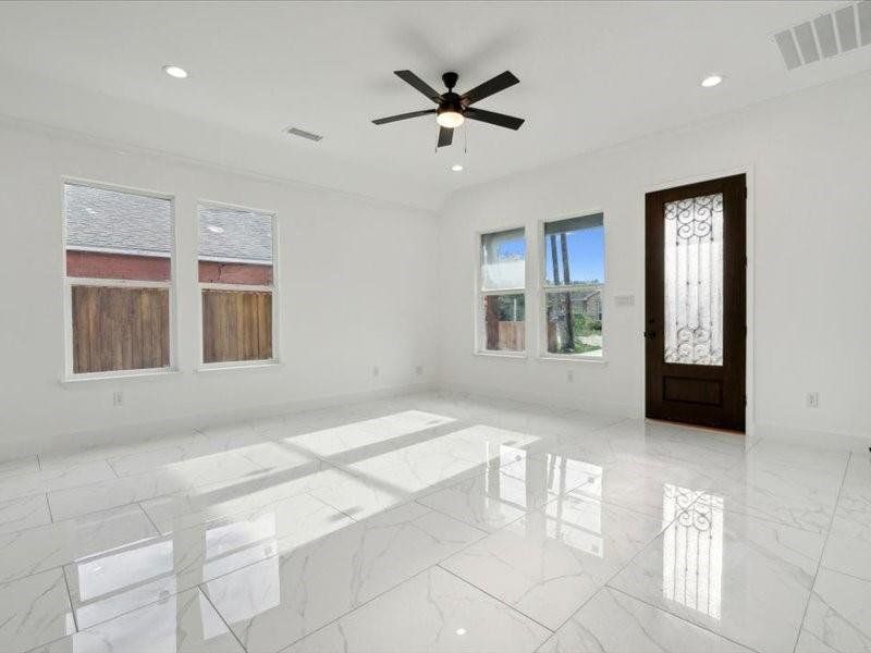 Tiled spare room featuring ceiling fan