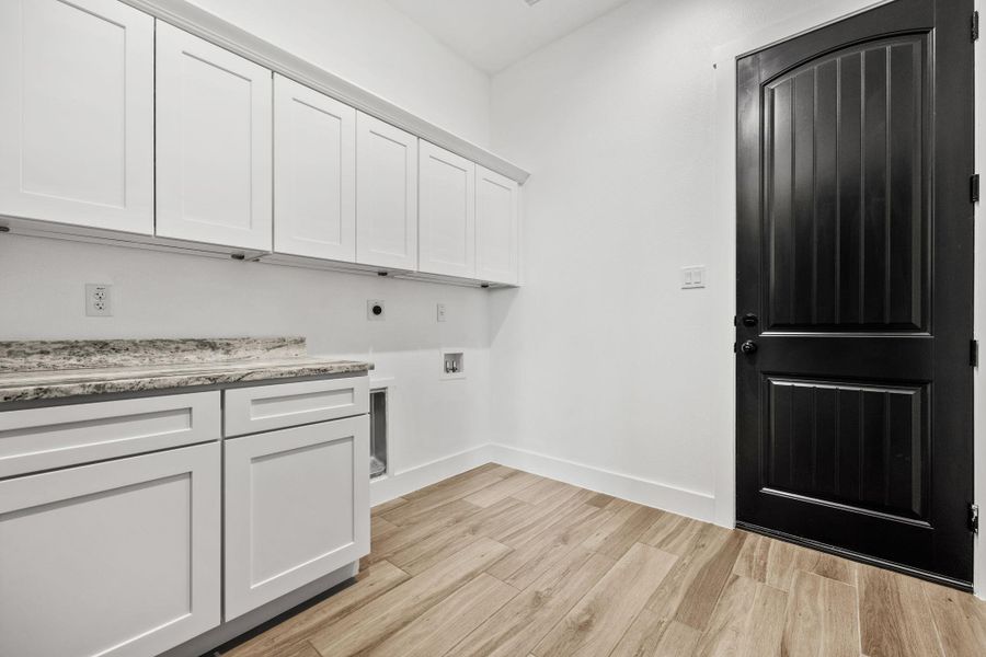 Laundry room featuring light wood-style flooring, cabinet space, hookup for a washing machine, and hookup for an electric dryer