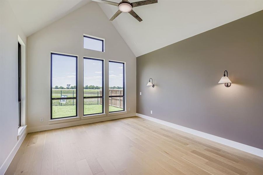 Unfurnished room featuring a ceiling fan, light wood-style flooring, and high vaulted ceiling
