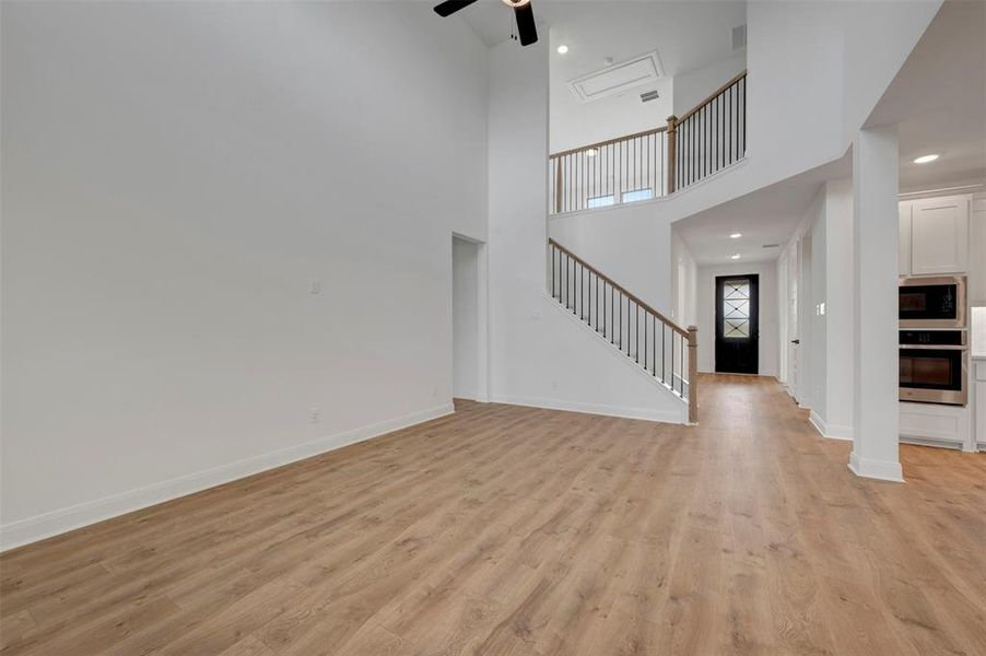 Unfurnished living room with recessed lighting, light wood-style flooring, a high ceiling, and ceiling fan
