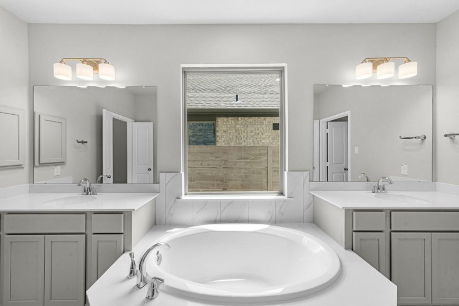 Double vanities, soaking tub, and separate shower in the luxurious primary bathroom.