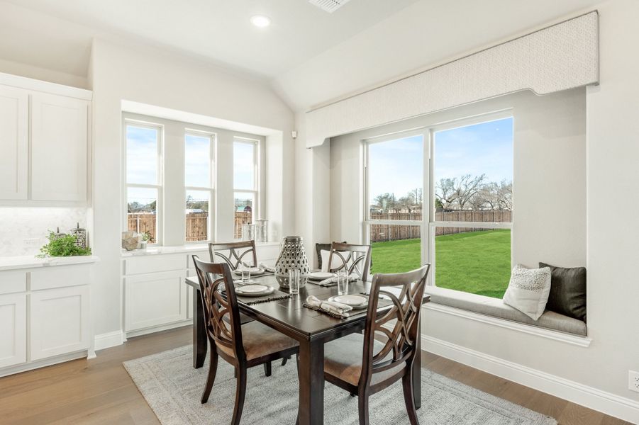 Breakfast nook with dark wood table, four chairs, window seat, and large windows overlooking backyard Breakfast nook with dark wood table, four chairs, window seat, and large windows overlooking backyard