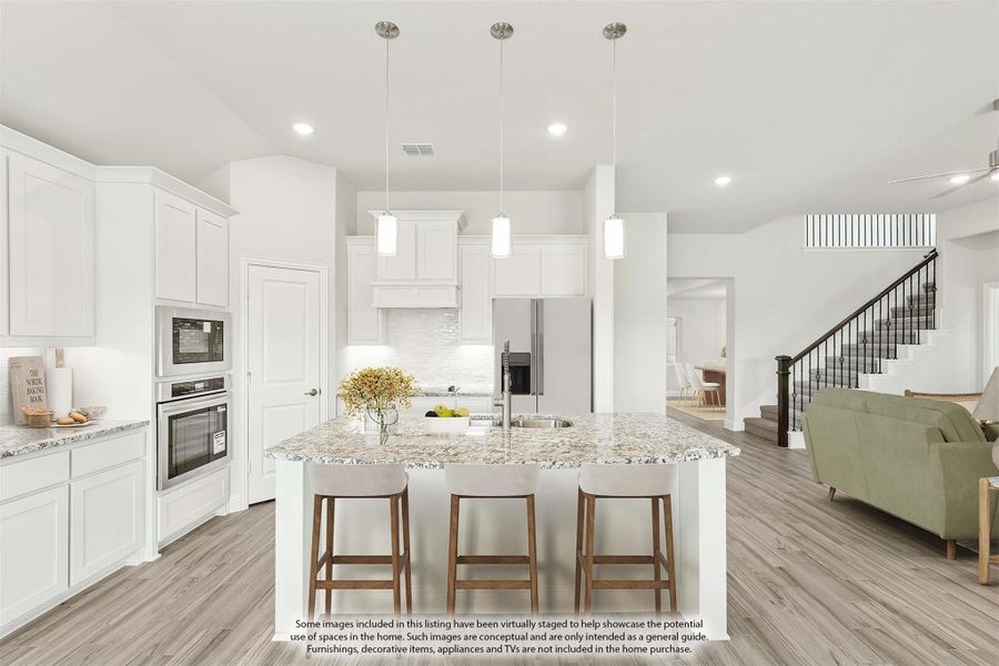 Open kitchen with white cabinets, granite island with three bar stools, and light wood floors