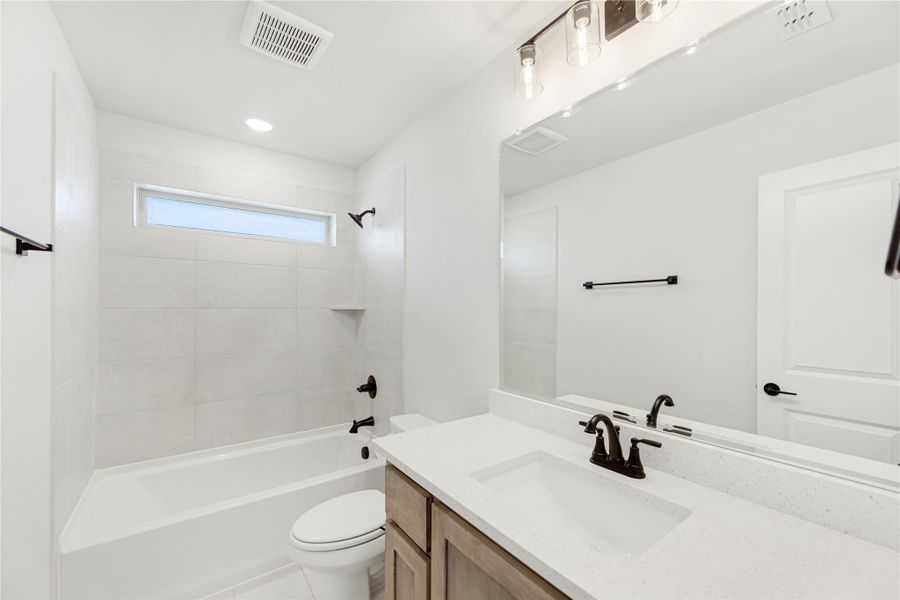 Bathroom with white quartz vanity, tiled tub-shower combo, and dark bronze fixtures