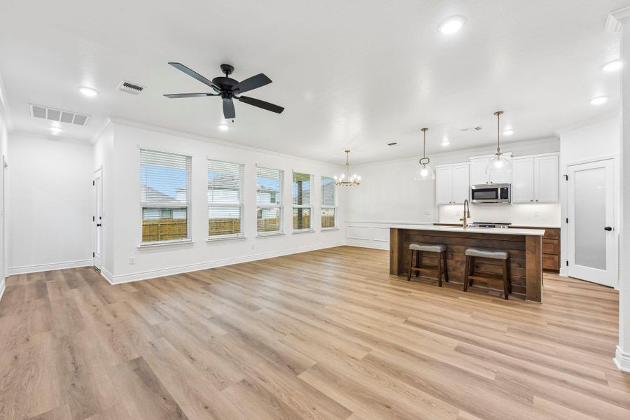 An open-concept living space blends seamlessly with a modern kitchen, featuring a central island and recessed lighting. An open-concept living space blends seamlessly with a modern kitchen, featuring a central island and recessed lighting.