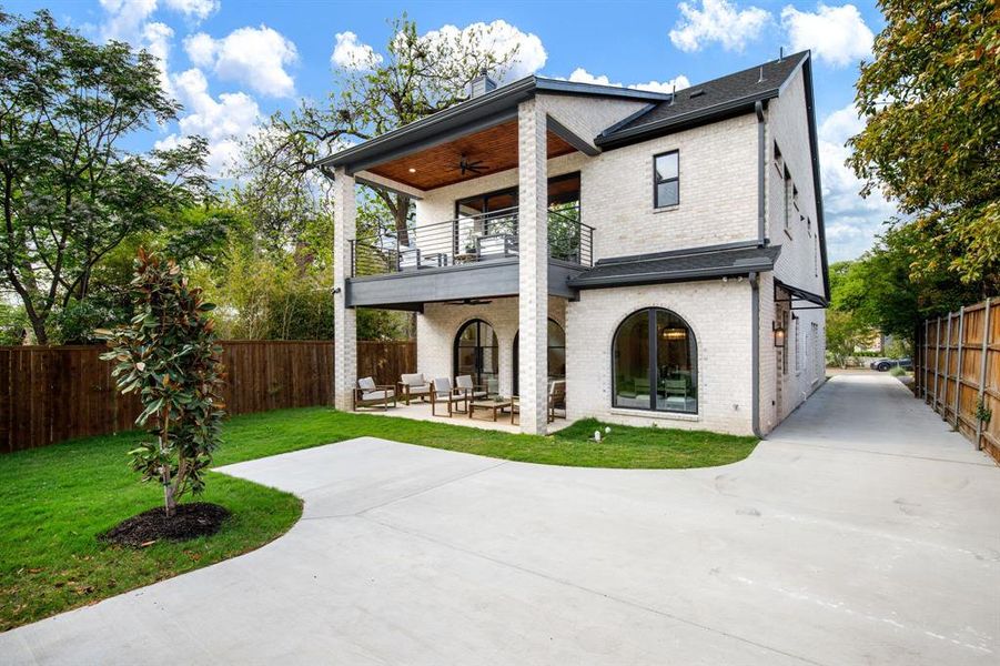 Contemporary brick residence featuring a second-story balcony with metal railings and a wood-paneled ceiling Contemporary brick residence featuring a second-story balcony with metal railings and a wood-paneled ceiling