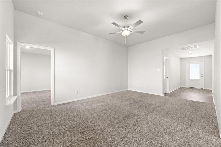 Empty room with ceiling fan and light carpet