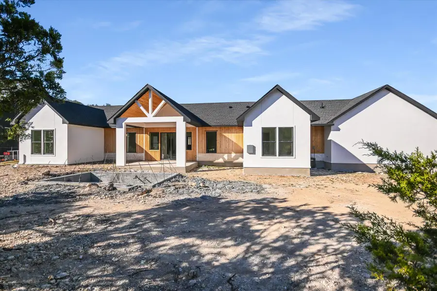 Rear view of house featuring a patio area, stucco siding, and roof with shingles