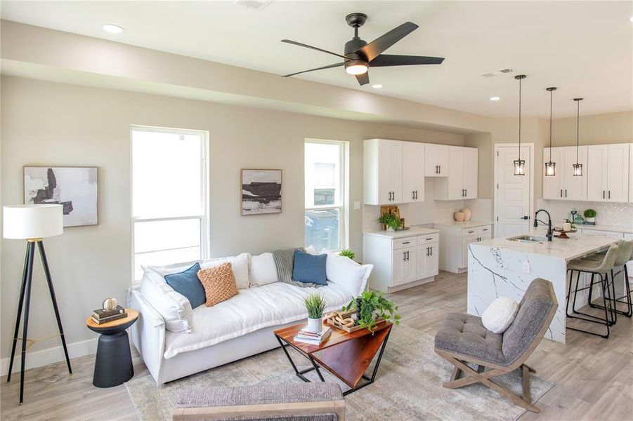 Living room featuring sink, light wood-type flooring, and ceiling fan