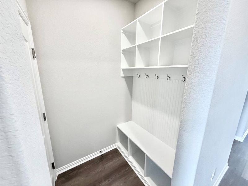 Mudroom featuring dark wood-style floors and a textured wall Mudroom featuring dark wood-style floors and a textured wall